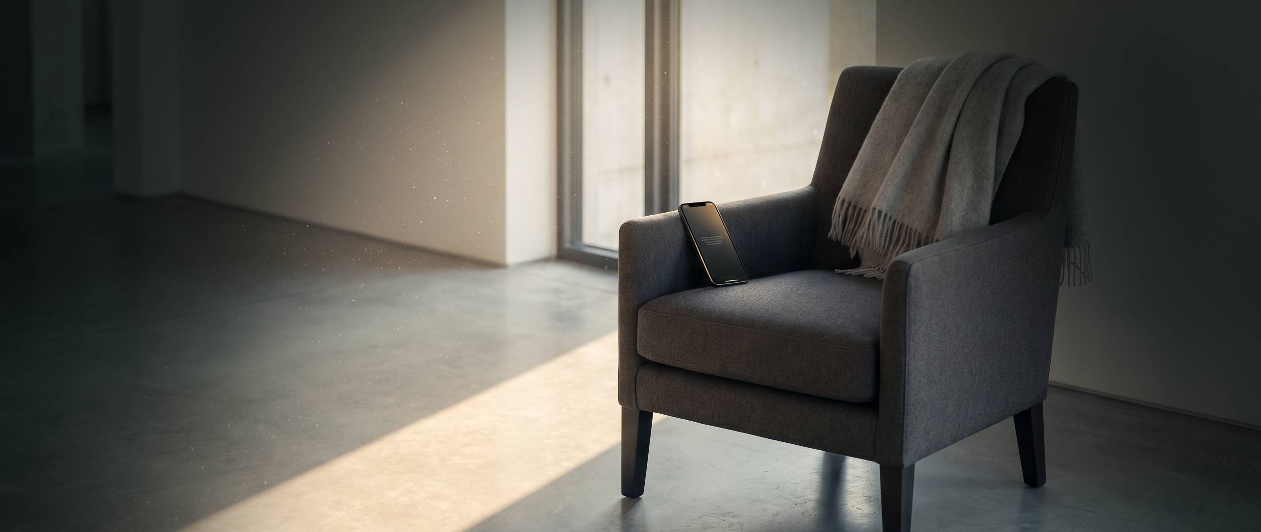 A quiet reading nook in golden hour light with a phone resting on a leather armchair beside a steaming teacup, an open notebook, and a small stack of cloth-bound books on a side table