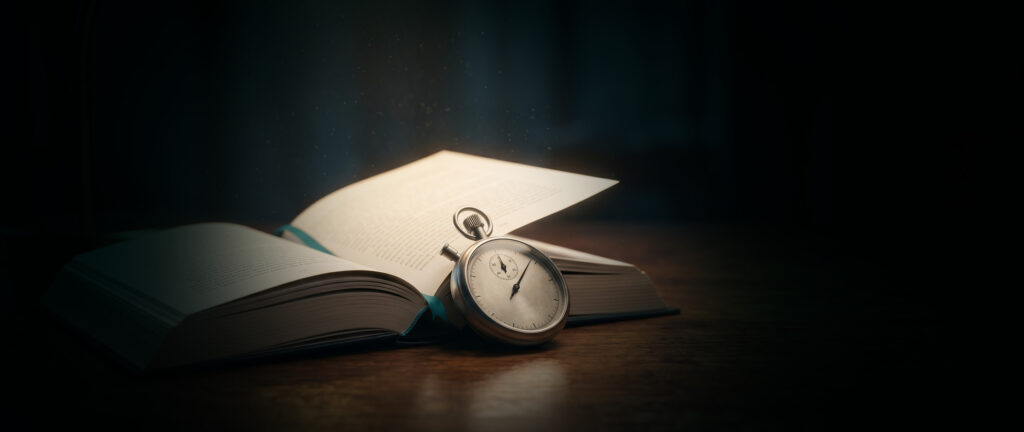 Open hardback book and vintage stopwatch on a warm wooden desk, representing the measurement of average reading speed